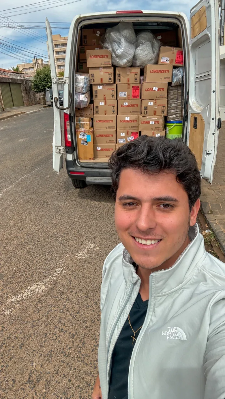 Natan ao lado de uma van carregada de caixas da sua operação.